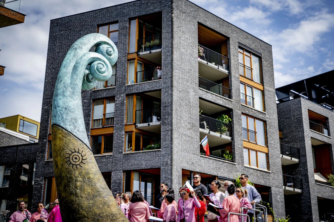 Monumen Ulu Kora di Lloydkade, Rotterdam, dengan paduan suara komunitas Maluku berbusana merah muda di latar depan